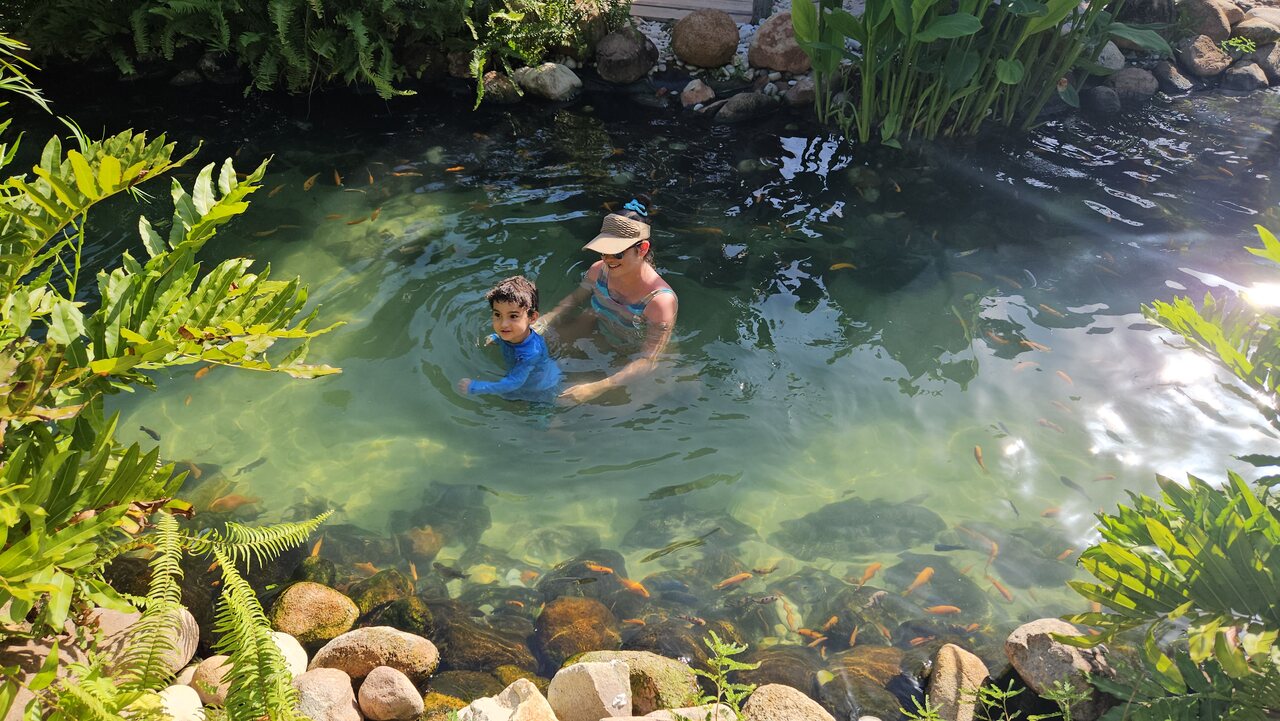 Lago natural em Maragogi com mãe e filho nadando Mãe e filho nadando em lago natural com águas cristalinas, rodeado por pedras, peixes e vegetação tropical.